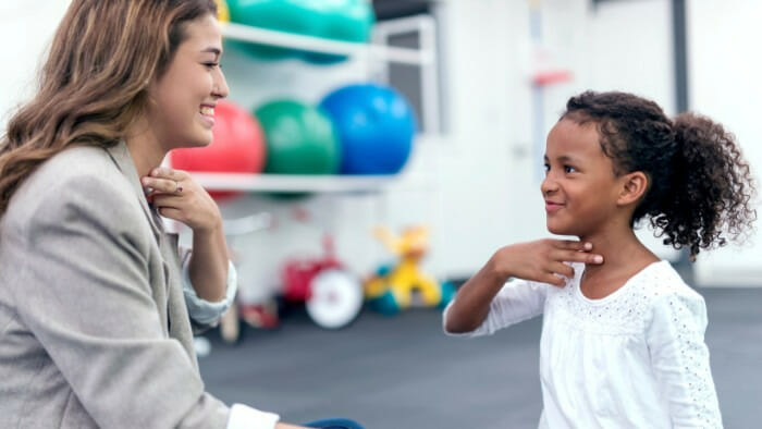 Speech Therapist touching throat with child